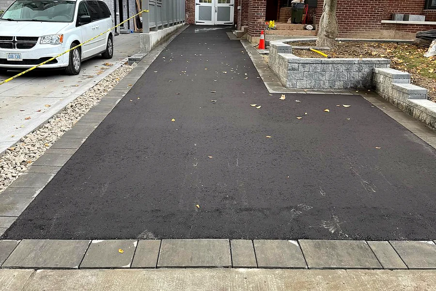 Long asphalt driveway edged with a stone paver border