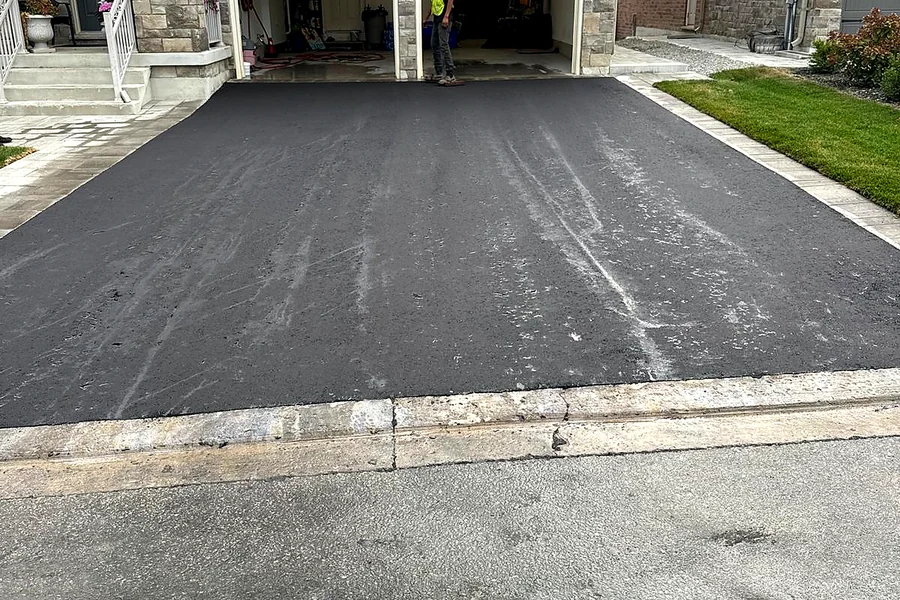 Newly paved asphalt driveway in front of a two-car garage