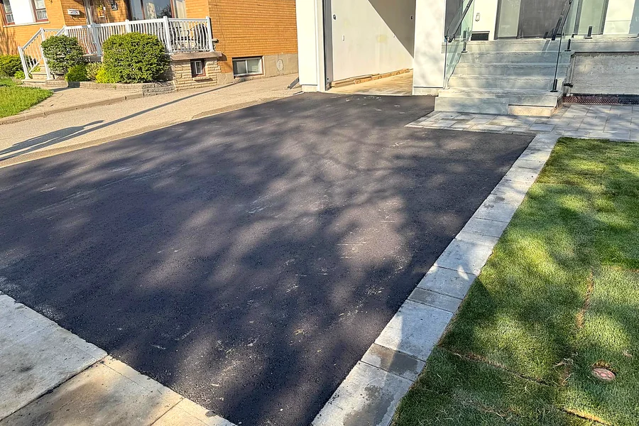 Asphalt driveway widened with a stone border along the lawn